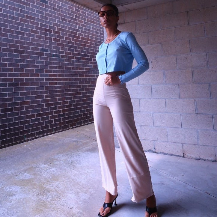 model wearing beige high waisted pants with blue cropped cardigan